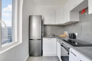 cocina con nevera de acero inoxidable y ventana en Appartement Refait À neuf 4 Couchages, en Levallois-Perret