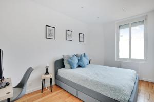 Dormitorio blanco con cama con almohadas azules en Appartement Refait À neuf 4 Couchages, en Levallois-Perret