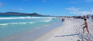 un groupe de personnes marchant sur la plage dans l'établissement Suítes Praia Do Foguete, à Cabo Frio