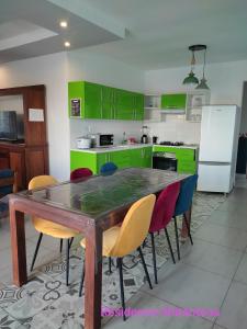 a kitchen with green cabinets and a wooden table and chairs at Résidence Ahitantsoa Appartement à l'étage in Mahajanga