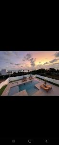 una gran piscina con bancos y una puesta de sol en PIPA Magnifique villa moderne en front de mer, en Tibau do Sul