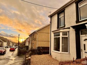 a house on a street with a sunset in the background at Modern Mountain Retreat in the Brecon Beacons in Ystradgynlais