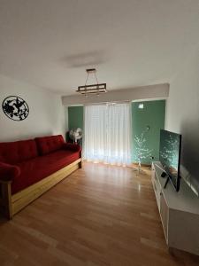 uma sala de estar com um sofá vermelho e uma televisão em Departamento Irigoyen em Trelew