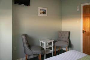 a bedroom with two chairs and a table and a bed at The Pipers Rest in Doolin