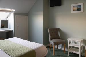 a bedroom with a bed and a chair and a television at The Pipers Rest in Doolin