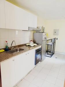 a kitchen with a sink and a refrigerator at Amplio apartamento El Eden cerca Embajada Americana y Solca - zona tranquila seguridad 24-7 in Quito