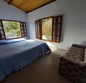 a bedroom with a bed and two windows at Reserva Som das Águas in Caparaó Velho