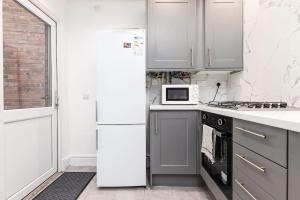 a white kitchen with a refrigerator and a microwave at Holiday Lodge, close to Nottingham City Centre in Nottingham +22 photos