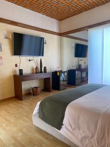 sypialnia z dużym łóżkiem i telewizorem z płaskim ekranem w obiekcie HOTEL BOUTIQUE CASA DEL BOSQUE w mieście Tlaxcala de Xicohténcatl