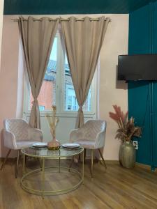 ein Wohnzimmer mit einem Tisch, 2 Stühlen und einem Fenster in der Unterkunft The Pink Blue in Lüttich