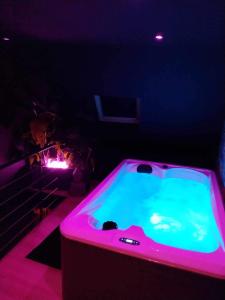 a dark room with a hot tub with purple lights at Chambre Noire in Solre-le-Château