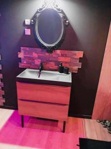 a bathroom with a sink and a mirror on a wall at Chambre Noire in Solre-le-Château