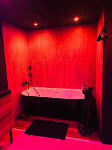 a red bathroom with a tub with a red wall at Chambre Noire in Solre-le-Château