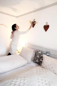Doppelzimmer mit Terrasse في دارليغن: امرأة تقف على سرير وهي ممسكة بزرع على الحائط