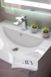 a towel with the letter k sitting on a bathroom sink at AVA PROPERTY RENTALS in Făgăraş