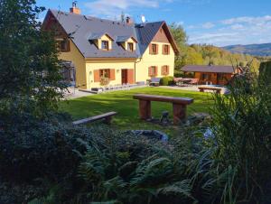 a large yellow house with a picnic table in front of it at Chata Esty in Bělá pod Pradědem