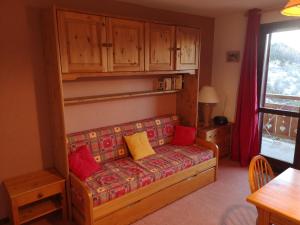 Una sala de estar con un sofá con cojines rojos y amarillos. en Studio coin montagne à Auris en Oisans avec vue magnifique, en Auris 22 fotos más