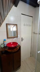 uma casa de banho com um lavatório vermelho e um chuveiro em Chale Bombinhas/Borto Belo em Porto Belo