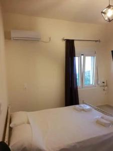 a bedroom with a white bed and a window at Damianakis Village Rethymno in Somatás