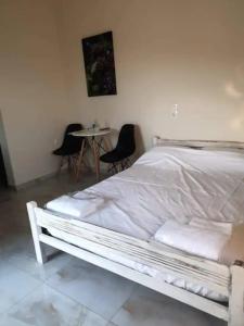 a white bed in a room with a table and chairs at Damianakis Village Rethymno in Somatás