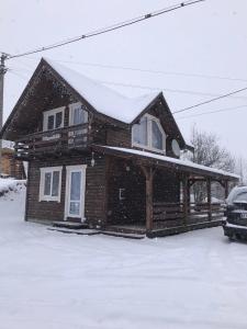 een houten huis met sneeuw op het dak bij Модрина in Vorochta