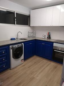 a kitchen with blue and white cabinets and a dishwasher at Hostal Mari, alquiler habitación privada en hostal, 6 habitaciones cerca de la universidad y aeropuerto Norte, 3 baños compartidos in La Laguna