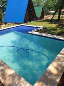 a pool of blue water with a surfboard in it at Cabañas Alpinas in San Bernardino