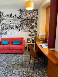 a living room with a red couch and a desk at Best Western Plus Hôtel Colbert in Châteauroux