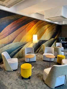 een lobby met stoelen en tafels en een kleurrijke muurschildering bij Best Western Plus Hôtel Colbert in Châteauroux