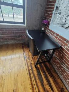 a black table and a chair in a room with a brick wall at Luxe Art Gallery in Saint Louis