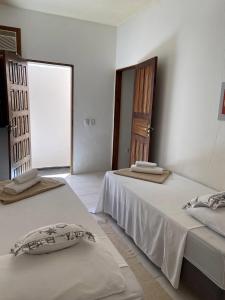 Duas camas num quarto branco com uma janela em Casa da Cristina em Trancoso