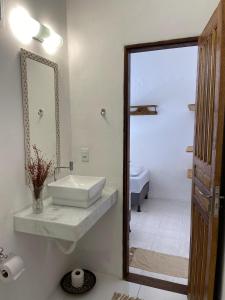 uma casa de banho branca com um lavatório e um espelho em Casa da Cristina em Trancoso
