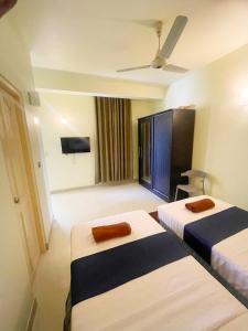 a hotel room with two beds and a flat screen tv at Oren Hotel Maldives in Maamigili
