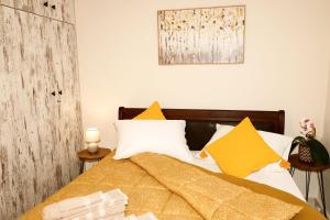 ein Schlafzimmer mit einem Bett mit gelben und weißen Kissen in der Unterkunft Poppys home in Piräus