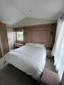 a bedroom with a large white bed and a window at 2-6 guests Holiday Chalet in Durdle Door in West Lulworth