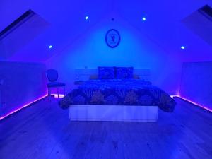 een slaapkamer met een bed met blauwe en paarse verlichting bij Charme & Caractères de Campagne in Tinténiac