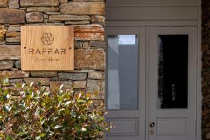 un cartel en una pared de piedra junto a una puerta en Raffar luxury houses en Tinos Town