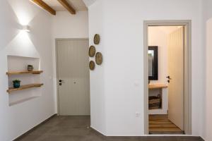 a hallway with a white wall and a door at Raffar luxury houses in Tinos