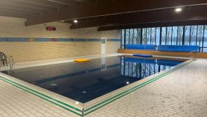 a large swimming pool in a large room at Huisje Hygge - luxe bungalow met grote tuin in Ewijk
