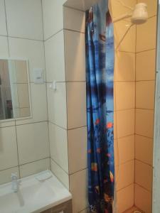 a bathroom with a shower curtain with a sink at Kitnet Avenida in Imbituba