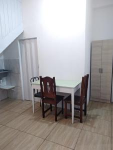 a dining room table with two chairs and a white table at Kitnet Avenida in Imbituba