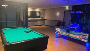 a room with a pool table and an arcade game at Huisje Hygge - luxe bungalow met grote tuin in Ewijk