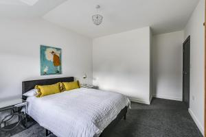 a white bedroom with a bed with a yellow pillow at Moselle House in Biggin Hill