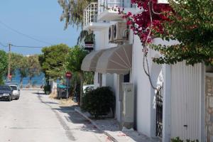 a white building with an awning next to a street at Seaside cushy studio in Kampos Paros