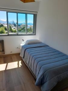 a bed in a room with a large window at MIRADOR DEL CENTRO BARILOCHE in San Carlos de Bariloche