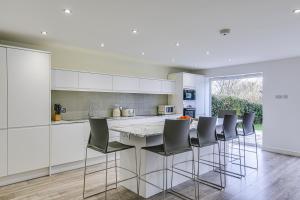 a kitchen with white cabinets and bar stools at Moselle House in Biggin Hill
