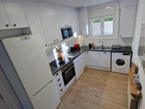 a kitchen with white cabinets and a white refrigerator at Apartamento CREMALLERA Ribes de Freser in Ribes de Freser