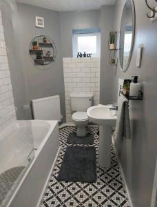 a bathroom with a tub and a toilet and a sink at 2 Bedroom Apartment in Exhall
