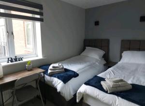 een slaapkamer met 2 bedden, een bureau en een raam bij 2 Bedroom Apartment in Exhall