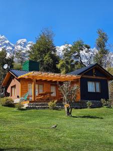 a log cabin with mountains in the background at La Yaya - Villa Turismo in El Bolsón